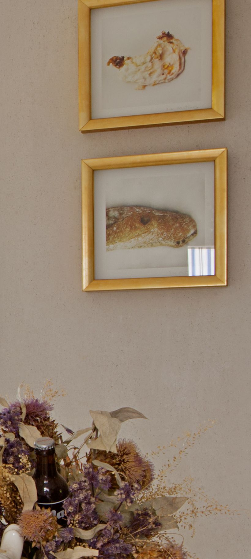 Dos obras enmarcadas en pan de oro sobre una pared de estuco claro